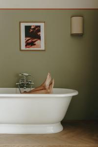 a person sitting in a bath tub with their feet in it at Parkhotel Mondschein, a Member of Design Hotels in Bolzano