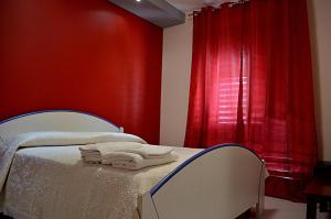 フォンダケッロにあるFondachello Mare dell'Etnaの赤い壁のベッドルーム1室(タオル付きのベッド1台付)