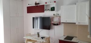 a kitchen with white cabinets and a tv on the wall at BlueCoast Apartment Vlore in Vlorë