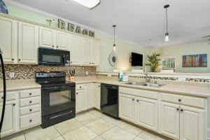 a kitchen with white cabinets and black appliances at Sun Sational in Myrtle Beach