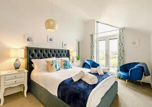 a bedroom with a large bed and blue chairs at Coastal Dreams in St Ives