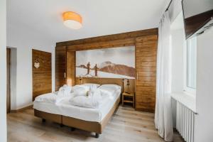 a bedroom with a bed with a painting on the wall at Family Hotel Gran Baita in Pozza di Fassa +113 photos