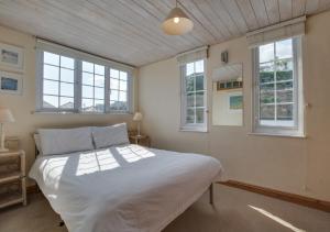 um quarto com uma grande cama branca e janelas em 3 Crab Rock Dolphin em St. Ives