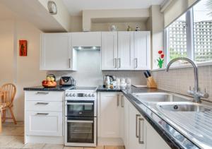 a kitchen with white cabinets and a sink at An Marghty 4a Carthew Terrace in St Ives