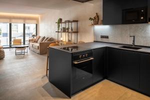 een keuken met zwarte apparatuur en een woonkamer bij TocToc Suites Olof Palme in Las Palmas de Gran Canaria