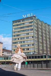 una mujer caminando por la calle frente a un hotel en Noli Sörnäinen, en Helsinki