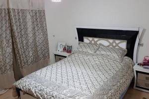 1 dormitorio con 1 cama con edredón blanco y negro en Appartement-résidence prestigia plage des Nations, en Rabat