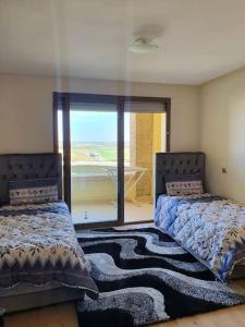 1 dormitorio con 2 camas y ventana con vistas en Appartement-résidence prestigia plage des Nations, en Rabat