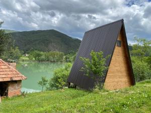 的住宿－Kamp jezero Stari Brod，湖畔的一座带黑色屋顶的小房子