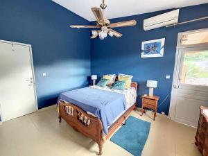 Saint-JosephにあるVilla Les 12 Zicaquesの青いベッドルーム(ベッド1台、天井ファン付)