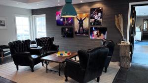 uma sala de espera com cadeiras e uma mesa e quadros na parede em Furuvik Havshotell 
