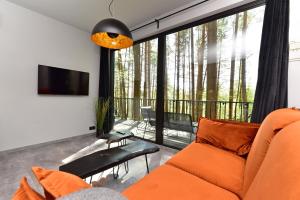 a living room with an orange couch and a balcony at Premium Forest Bungalow with HOT TUB in Ažuluokesa
