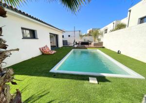 a backyard with a swimming pool and green grass at Villa contemporaine avec piscine chauffée proche des plages in Sauvian