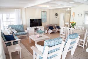 uma sala de estar com uma mesa e cadeiras e uma televisão em Barefoot Lodge, Mossel Bay em Mossel Bay