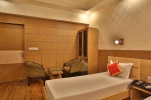 a bedroom with a bed and two chairs and a table at Hotel The Grand Chandiram in Kota