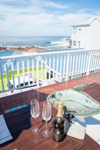 Mossel Bay的住宿－Barefoot Lodge, Mossel Bay，一张桌子,上面放着两杯酒和一瓶葡萄酒