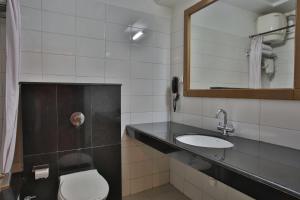 a bathroom with a toilet and a sink and a mirror at Hotel The Grand Chandiram in Kota