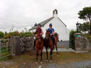 dwoje ludzi jeżdżących konno przed budynkiem w obiekcie The Burren Art Gallery built in 1798 w mieście Tubber
