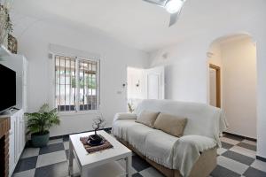 a white living room with a couch and a table at Villa Manuel in Chiclana de la Frontera