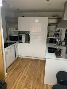 a kitchen with white cabinets and a wooden floor at Liverpool City Centre Apartment in Liverpool