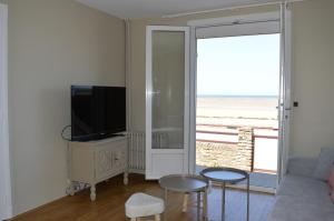 a living room with a couch and a tv at L'Estran - maison sur la digue avec vue mer in Courseulles-sur-Mer