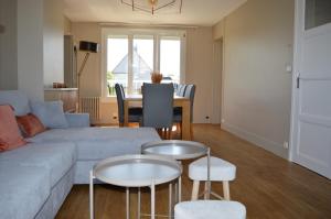a living room with a couch and two tables at L'Estran - maison sur la digue avec vue mer in Courseulles-sur-Mer
