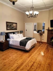 um quarto com uma cama grande e piso em madeira em Uitenhage Apartment - 4 Graaff-Reinet Rd em Uitenhage