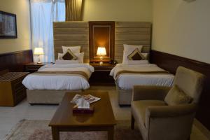 Al Nafoura Hotel في لاهور: غرفة فندقية بسريرين واريكة