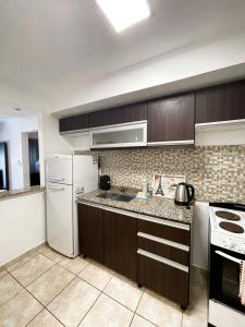 cocina con armarios marrones y nevera blanca en Regia Apartamentos Posadas en Posadas
