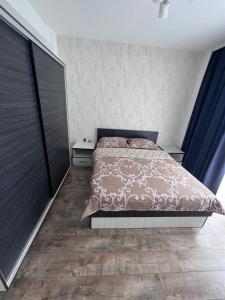 a bedroom with a bed and a wooden floor at Nesta Apartament in Fălticeni