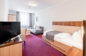 a hotel room with a bed and a flat screen tv at Sporthotel Neuruppin in Neuruppin