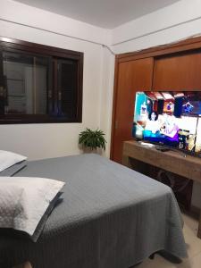 een slaapkamer met een bed en een flatscreen-tv bij Residencial com CHURRASQUElRA! in Bento Gonçalves
