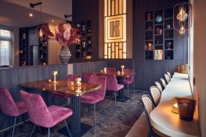 a restaurant with pink chairs and tables in a room at The Yard hotel Noordkade in Veghel