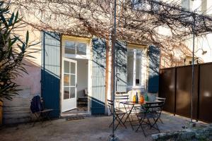 um pátio com uma mesa e cadeiras em frente a uma casa em Maison Ventoux em Carpentras