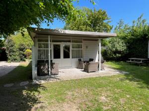 a screened in porch with chairs and a picnic table at Gezellige bungalow op steenworp afstand van het strand in Ouddorp