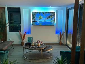 ein Wohnzimmer mit einem Tisch und einem Gemälde an der Wand in der Unterkunft Escapade Zen Oasis Tropicale Spa Privatif in Loon-Plage