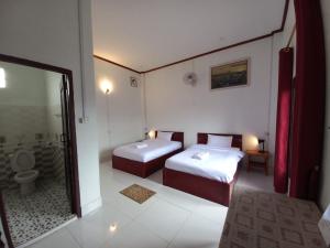 a room with two beds and a bathroom with a toilet at Sipanya Guesthouse in Muang Phônsavan