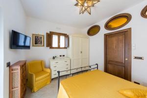 a bedroom with a yellow bed and a chair at B&B La Casa Nel Giardino in Piano di Sorrento
