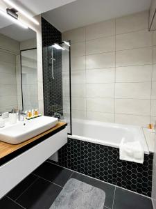 a bathroom with a white sink and a bath tub at Alegria Avantgarden Brasov in Braşov