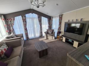a living room with a couch and a flat screen tv at Rockley Park, Gorse Hill 39 in Lytchett Minster