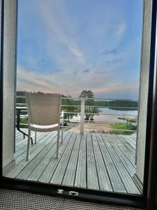a chair on a deck with a view of the water at Pokoje Gościnne Villa Plaza in Ruciane-Nida