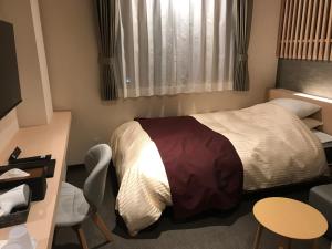 um quarto com uma cama, uma mesa e uma cadeira em Aizu Tsuruya Hotel em Aizuwakamatsu