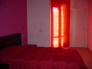 um quarto vermelho com uma cama e uma janela em Hotel I Colori em SantʼAntìoco