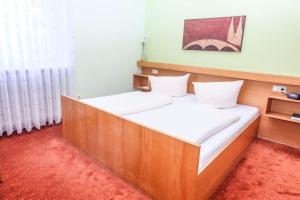 a bedroom with a wooden bed with white sheets at Hotel-Restaurant Wiendl in Regensburg