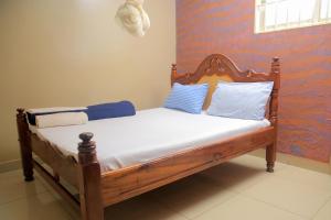 una cama de madera con almohadas azules y blancas. en Perfect Motel en Kampala