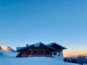 une cabane en rondins dans la neige avec des montagnes en arrière-plan dans l'établissement Au Alm, à Söll