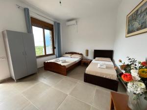 1 dormitorio con 2 camas y ventana en KAFUL APARTMENTS en Qeparo