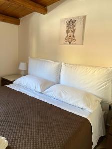 - un lit avec des oreillers blancs et une photo sur le mur dans l'établissement Nikuzza Holiday House, à Noto
