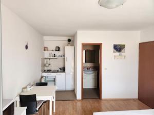 a white kitchen with a table and a dining room at Apartmani Neva Supetar in Supetar