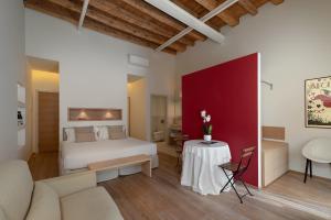 Massimago Wine Suites في فيرونا: غرفة نوم بسرير ابيض وجدار باللهجة الحمراء